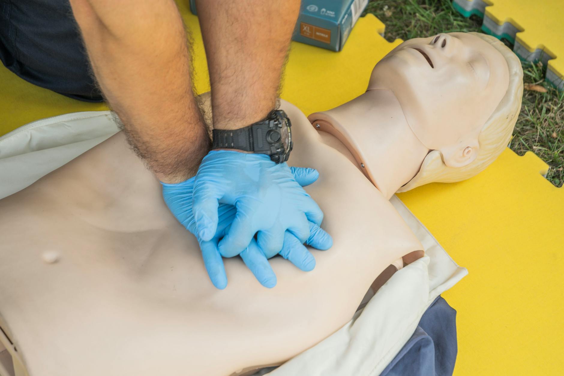 Mains pratiquant un massage cardiaque sur mannequin de formation SST